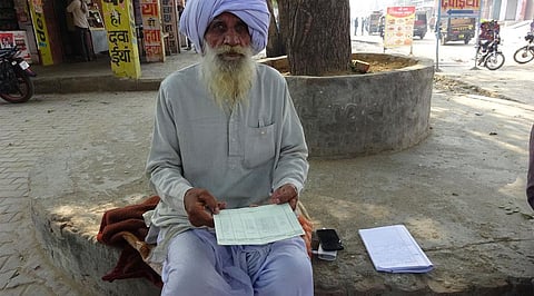 A farmer in front of bank, with his bank pass books showing crop insurance premium deduction from their bank accounts without his consent (Credit: Vineet Kumar/CSE)
