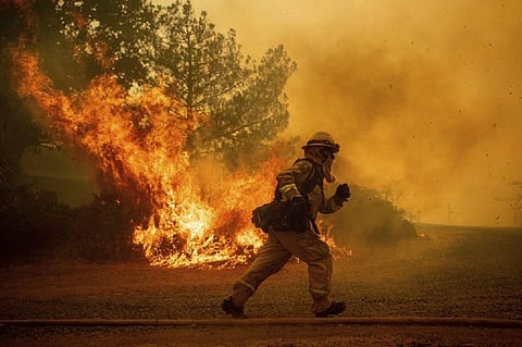 A firefighter runs after trying to save a home in Lakeport, California, suffering its biggest fires ever. AP Photo/Noah Berger
