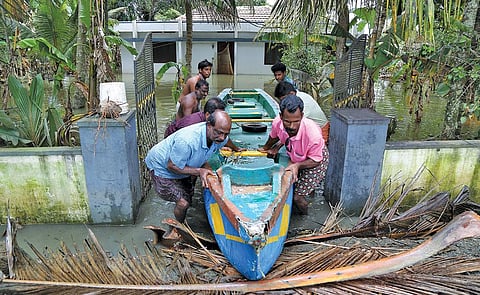 अलेप्पी जिले के कुट्टानाड में 24 अगस्त को बाढ़ प्रभावित एक घर से नाव को धक्का देते लोग (रॉयटर्स)