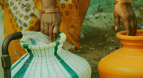 A rural woman fills vessels with water. Photo: Getty Images