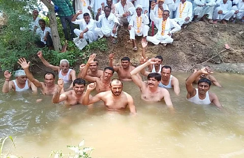 सिरसा के ऐलनाबाद डिस्ट्रीब्यूटरी के पानी में धरना देते किसान, जबकि आमरण अनशन पर बैठे किसान। फोटो: शील भारद्वाज
