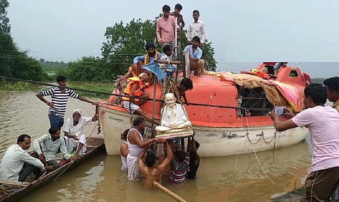 सरदार सरोवर बांध का जलस्तर बढ़ने के कारण डूब चुके गांव चिखल्दा से महात्मा गांधी की मूर्ति को हटाते नर्मदा बचाओ आंदोलन के कार्यकर्ता। फोटो- रहमत