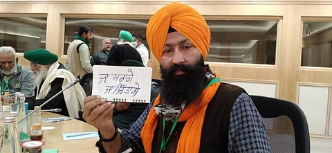 A delegate during the talks January 8, holds a placard which says in Gurmukhi: We will die or we will win. Photo: @ManuManjit1 / Twitter