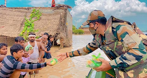उत्तर प्रदेश के जालौन में बाढ़ पीड़ितों को राहत सामग्री देते सेना के जवान। फोटो: twitter/@NorthernComd_IA