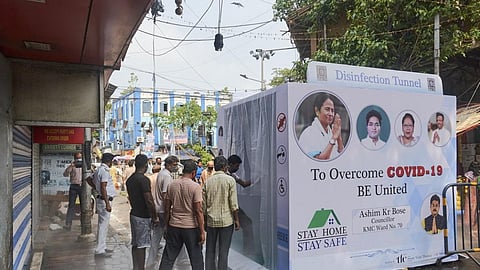 People standing in queue, waiting to enter into a COVID disinfectant tunnel, setup by Kolkata Municipal Corporation (KMC) health dept. at the entrance of a market in Bhowanipore, Kolkata. Photo: istock