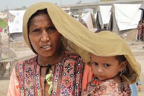 1. अपनी चार साल की बच्ची को गर्मी से बचाने की जद्दोजहद करती पाकिस्तान के सिंध प्रान्त में एक महिला; फोटो: फाइल फोटो: हीरा हाशमी/ यूएनडीपी