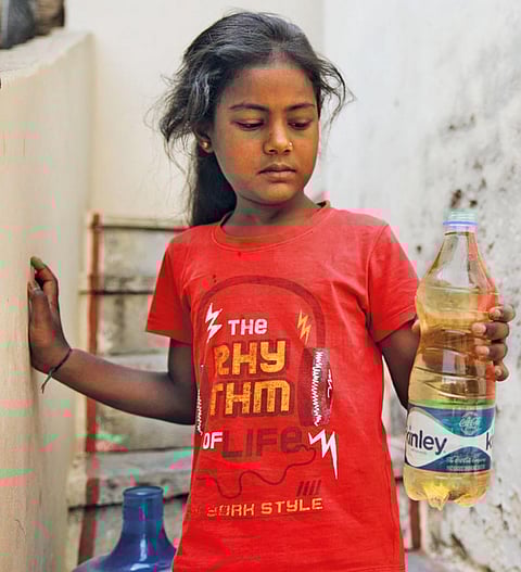 बिछड़ी गांव  के पास घर से बोरिंग में निकल रहे लाल एसिडिक पानी का नमूना लेकर आती पीड़िता  (फोटो: विकास चौधरी/सीएसई)