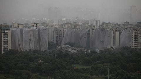 A cloud of dust hangs over the implosion site in Noida August 28. Notice the standing buildings covered with sheets to protect them from dust. Photo: Vikas Choudhary / CSE