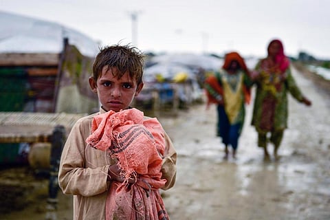 पाकिस्तान में आई भीषण बाढ़ के बाद अपने बिखरे सामान को बटोरता बच्चा; फोटो: सामी मालिक/ यूनिसेफ