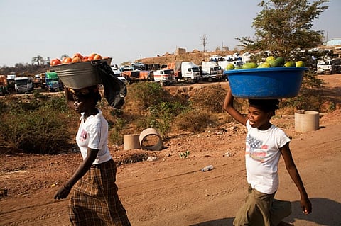 Hawkers carry their produce to the market walking past a truck yard on on the border of Zambia and Zimbabwe. Photo: Gideon Mendel/Corbis/Getty Images