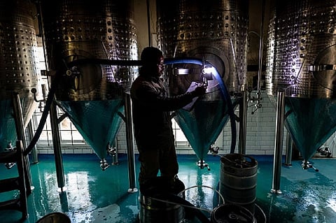 An employee makes fermentation notes by torchlight during a power outage period at a brewery in Cape Town, South Africa. Photo: Dwayne Senior/Bloomberg via Getty Images