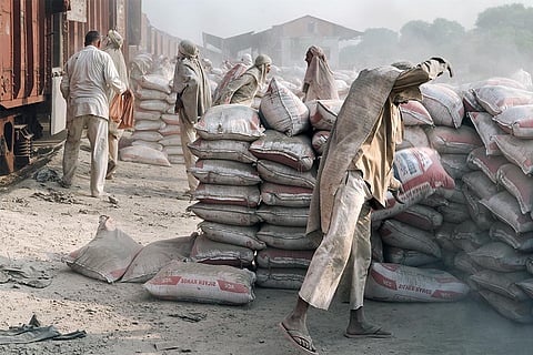 मथुरा में चिलचिलाती गर्मी में ट्रेन से धूल भरी सीमेंट की बोरियां उतारते मजदूर; फोटो: आईस्टॉक
