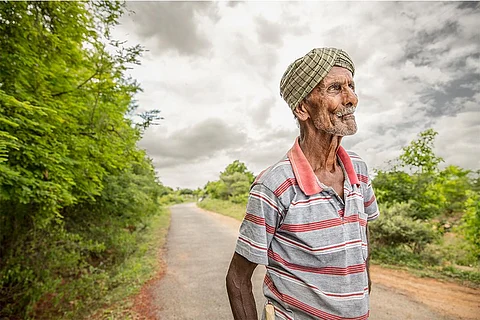 बारिश से पहले बादलों को निहारता किसान; फोटो: आईस्टॉक