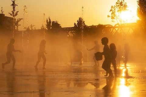 गर्मी और लू से बचने के लिए स्पेन के मैड्रिड में फव्वारों से निकलते पानी के साथ खेलते बच्चे; फोटो: आईस्टॉक