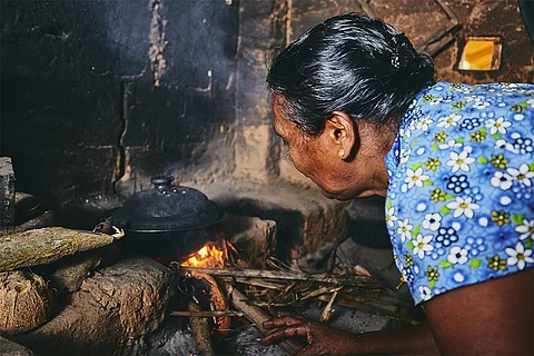 श्रीलंका में चूल्हे पर खाना तैयार करती महिला; फोटो: आईस्टॉक