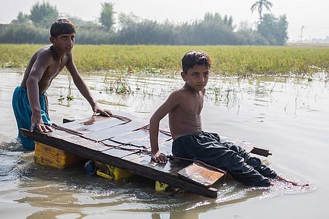 पाकिस्तान के सिंध प्रान्त के जैकोबाबाद में बाढ़ के बीच से होकर घर जाते बच्चे; फोटो: साइना बशीर/ यूनिसेफ