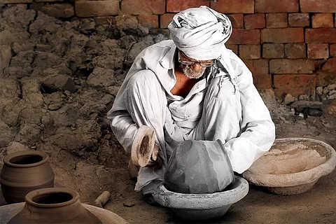 अपने बर्तनों को उचित आकार देने के लिए जद्दोजहद करता उत्तर भारत में एक पारंपरिक कुम्हार; फोटो: आईस्टॉक