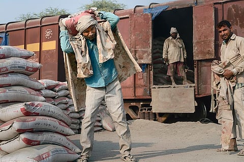 मथुरा में मालगाड़ी से सीमेंट की बोरियां उतारते मजदूर; फोटो: आईस्टॉक