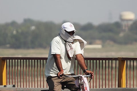प्रयागराज में गंगा किनारे भीषण गर्मी और लू के थपेड़ों के बीच जाता एक साइकिल सवार; फोटो: आईस्टॉक