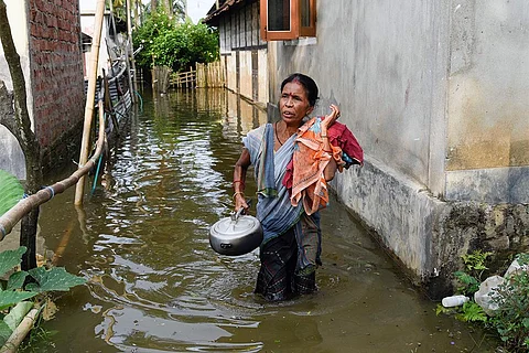असम में बाढ़ से जद्दोजहद करती स्थानीय महिला; फोटो: आईस्टॉक