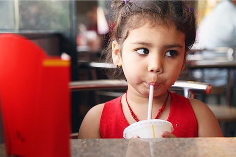 कैफे में कोल्ड ड्रिंक का आनन्द लेती बच्ची; फोटो: आईस्टॉक