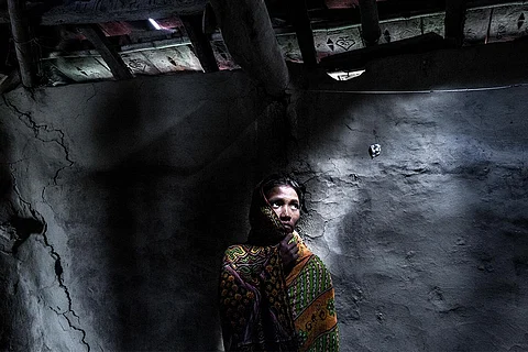समुद्र के बढ़ते जल स्तर से क्षतिग्रस्त अपने घर के सामने खड़ी 25 वर्षीय महिला; फोटो: सुप्रतिम भट्टाचार्य/ आईस्टॉक