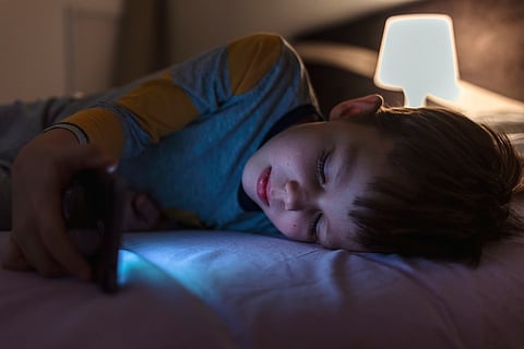 Cropped shot of a young boy sleeping with a cellphone in hand at home.