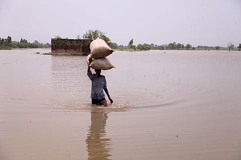 Farmer carrying sack on the head through a flooded region