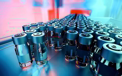 Close-up of medicine glass vials on a pharmaceutical production line, with metal caps and blank labels, moving forward