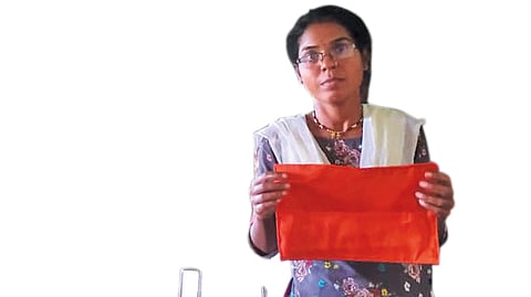 A volunteer with SPARSH makes a reusable cloth pad for menstruating women of the Madia community in Gadchiroli district