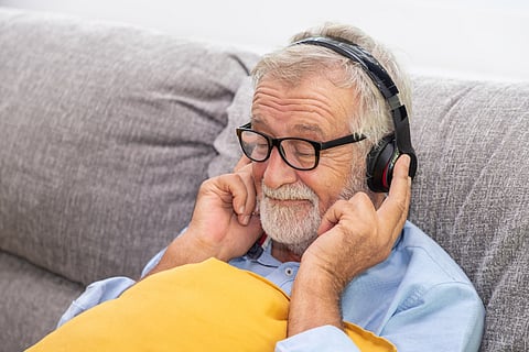 Senior old man eldery enjoy listening to music with headphone on couch sofa