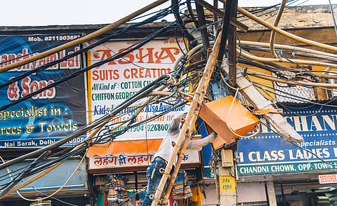 Electric cables chaos on a Old Delhi street. Engineer at work, repairing electric cables