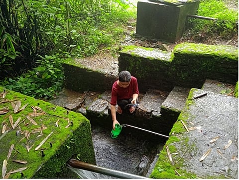 A young woman measures the spring’s discharge.
