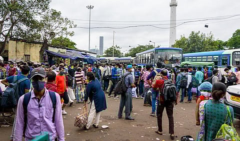 Migrant workers with masks wait at a bus stand during the COVID-19 unlock period in Kolkata in October 2020. Photo: iStock