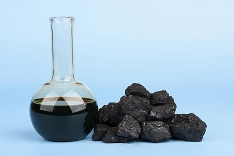Crude oil (from which natural gas is made) in a beaker, alongside black hard coal lumps. Photo for representation. Courtesy: iStock