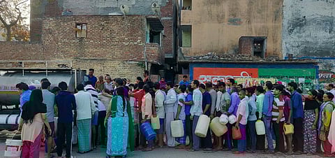 People queueing to collect water from a Delhi Jal board tanker.