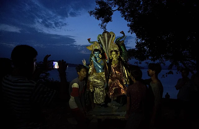 गुवाहाटी में झूलन यात्रा के दौरान भगवान कृष्ण और राधा की मूर्तियों का ब्रह्मपुत्र नदी में विसर्जन करने जाते लोग.