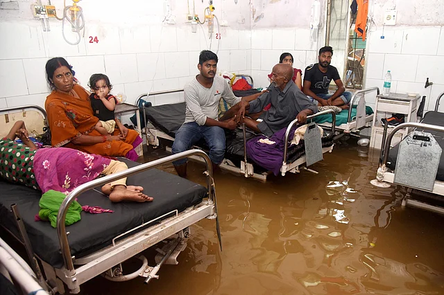 पटना में नालंदा मेडिकल कॉलेज अस्पताल के एक वार्ड में जलभराव से परेशान मरीज और तीमारदार 