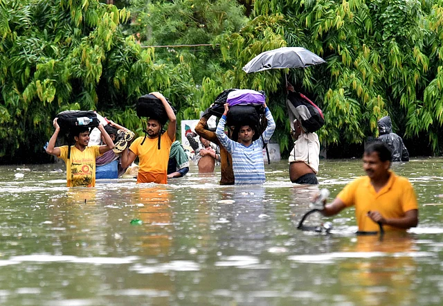 पटना में भारी बारिश के दौरान बाढ़ में डूबी सड़क से गुजरते लोग. 