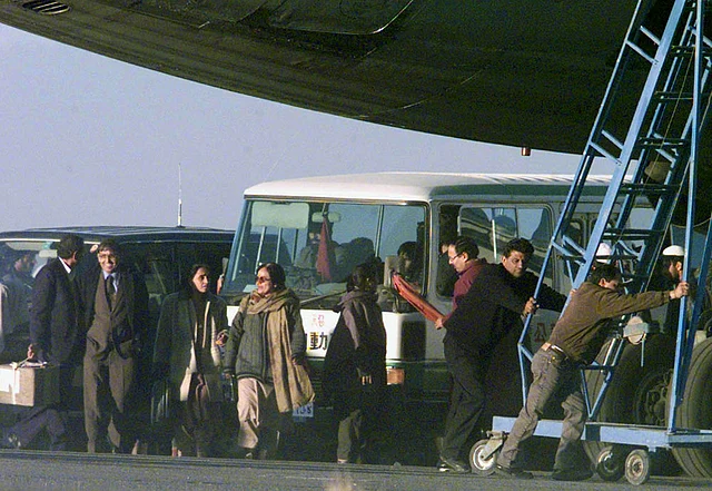 Freed passengers of the hijacked Indian Airlines plane prepare to board a minibus as workers push a staircase away from the plane at Kandahar airport 