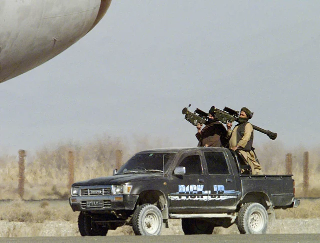 Two Taliban militiamen, with U.S.-made Stinger surface-to-air missiles upon their shoulders standby close to the hijacked Indian airliner at Kandahar airport 