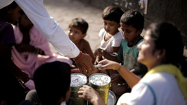 A <i>dabbawala</i> delivers a tiffin marked with the ‘share’ sticker to an NGO volunteer and slum children (Photo: Youtube/<a href="https://www.youtube.com/watch?v=UyT_bi-20e4">Rahul Bhatt</a>)