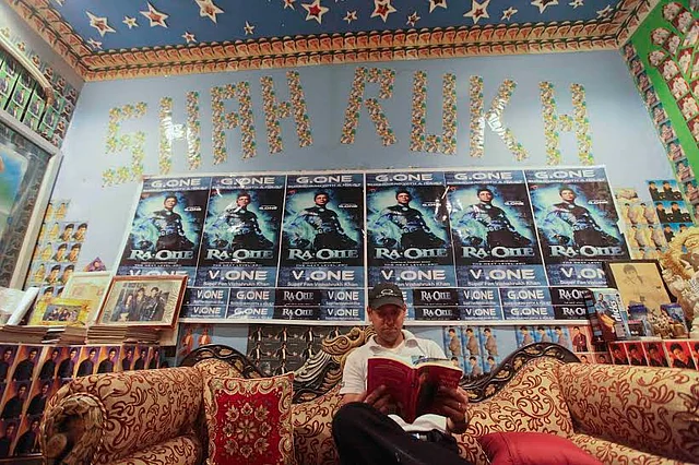Vishal reading SRK’s biography, surrounded by posters of <i>Ra.One</i>.