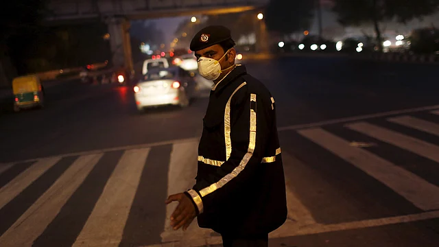 A traffic policeman wears a mask to protect himself from dust and air pollution as he signals to drivers in New Delhi, December 23, 2015. (Photo: Reuters)