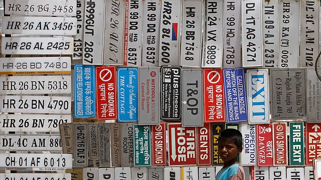 A boy stands in front of displayed car number plates and other signs at an automobile market in Gurgaon on the outskirts of New Delhi. (File photo: Reuters)