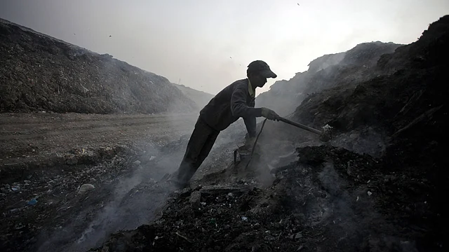 A scavenger sifts through ashes of waste for scrap metal in a garbage dump on the outskirts of New Delhi. (File photo: Reuters)