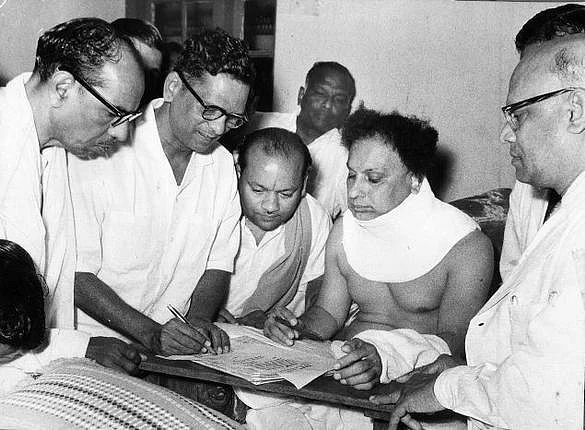 MGR, wearing a neck cast in his hospital bed, signs his nomination papers for the St Thomas Mount constituency.