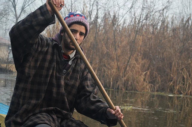A young man sails his Shikara on Dal Lake as he moves from his houseboat towards the city.