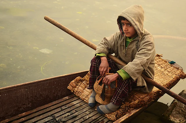 A little boy waits for his father in his Shikara. He holds a Kangri or a local fire pot in his hand as temperature in Srinagar dips on New Year day.