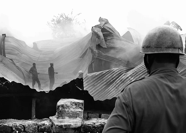 A fireman looks at his fellow colleagues as they try to put down the fire. (Photo courtesy: Sameer Khan)